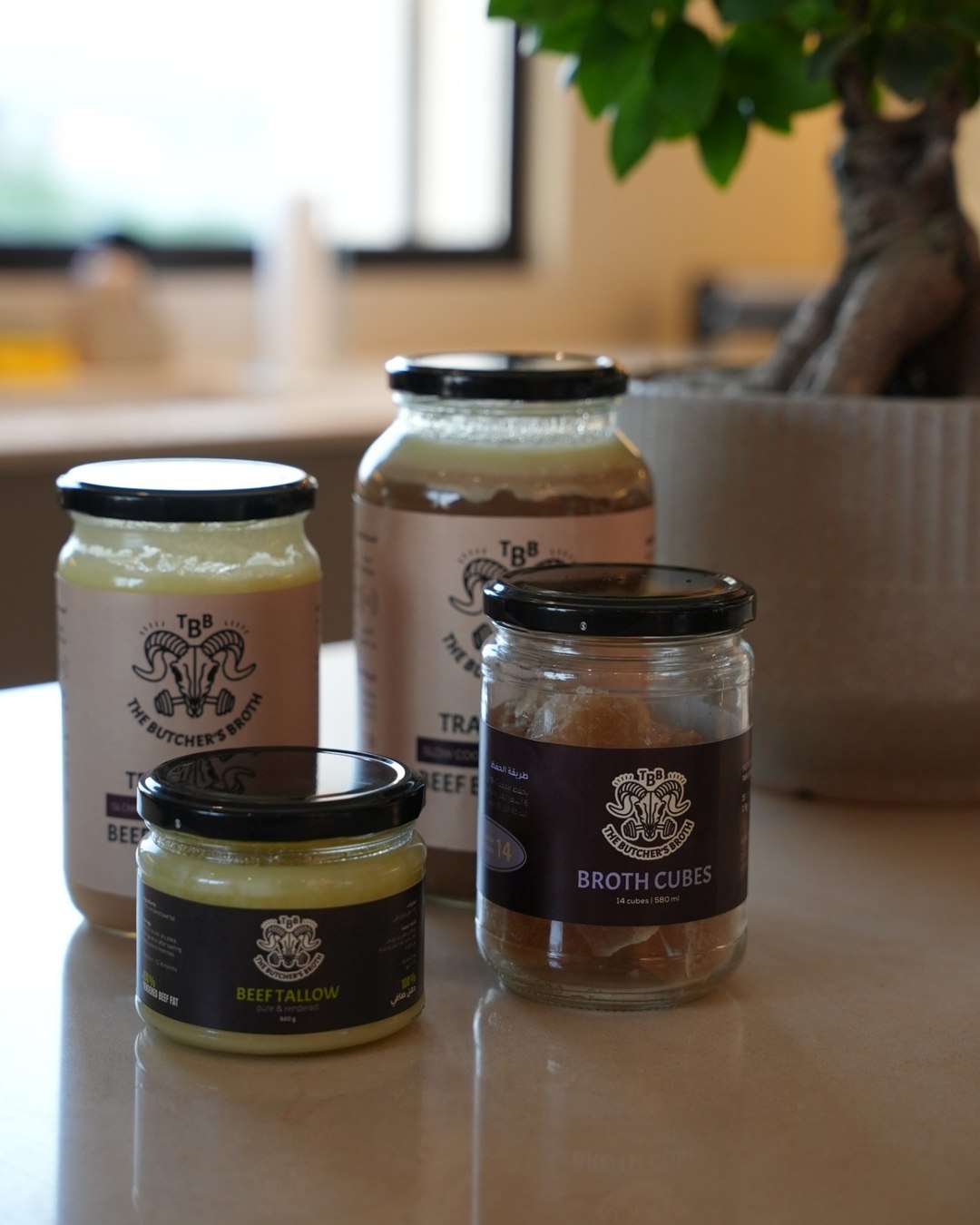 The full Butcher's Broth range on a kitchen counter: 720 ml and 1300 ml jars of beef bone broth, beef tallow and a jar of broth cubes